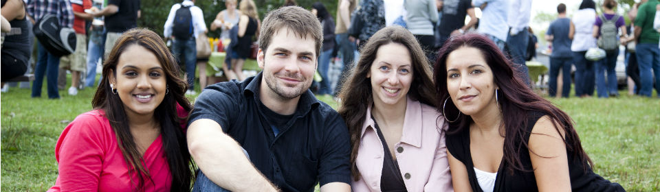 Group of students sitting outside on the grass facing the camera